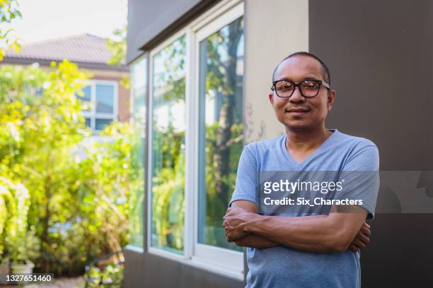 portrait of asian mature men standing in front or back yard outdoors at home, looking at camera - indonesian ethnicity stock pictures, royalty-free photos & images