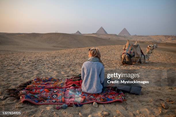 woman watches sunset at the giza pyramids, she looks across the sahara desert - giza pyramids stock pictures, royalty-free photos & images