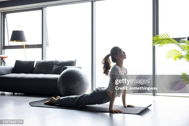 アジアの女性は自宅でヨガをする - stretching ストックフォトと画像