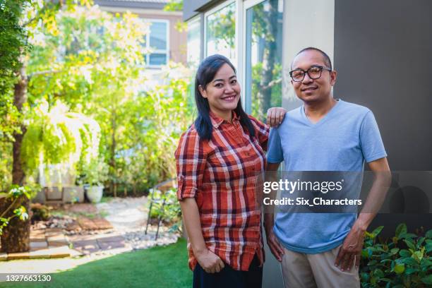 portrait of asian mature couple standing in front or back yard outdoors at home, looking at camera - business mature couple portrait bildbanksfoton och bilder