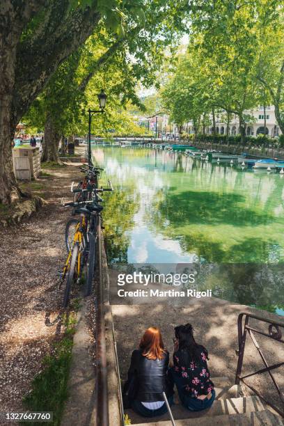 deux femmes se reposant devant le canal d’annecy au printemps - haute-savoie, france - lac d'annecy photos et images de collection