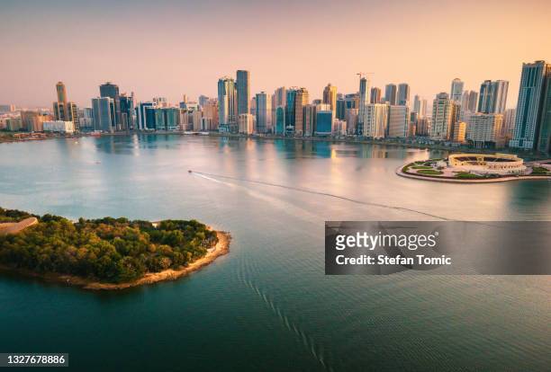 emirate of sharjah cityscape waterfront rising above al noor island at city downtown in the uae - island stock pictures, royalty-free photos & images