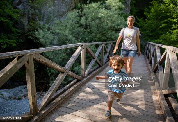 playful toddler having fun during family hike - mother running stockfoto's en -beelden