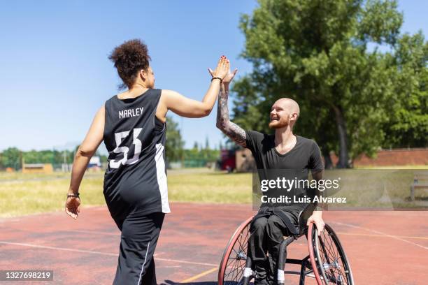 wheelchair basketball player high fiving a female coach on court - beruf sport stock-fotos und bilder