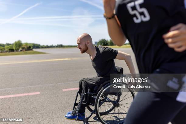 man in wheelchair with a woman running along him on old runway - tempelhof airport stock pictures, royalty-free photos & images