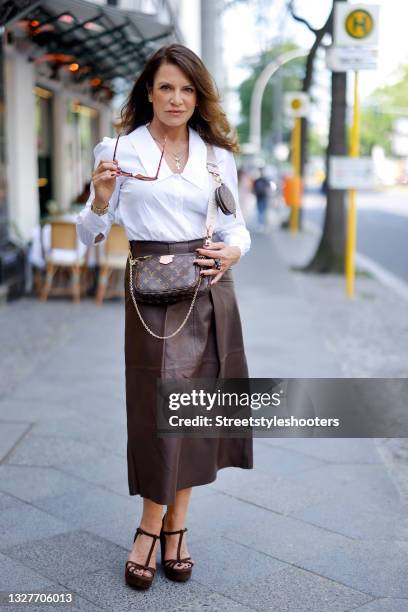 German actress Christine Neubauer wearing a white blouse by Riani, a brown leather maxi skirt by Riani, a gold bracelet by Chloe, brown sandals by...