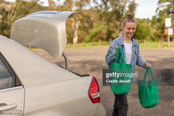 mujer joven sacando de compras de su coche - bolsa reutilizable fotografías e imágenes de stock