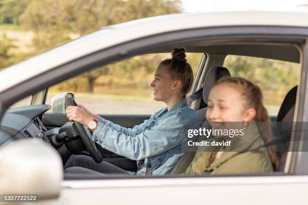 proud young woman driving friends in her first car - driving australia stock pictures, royalty-free photos & images