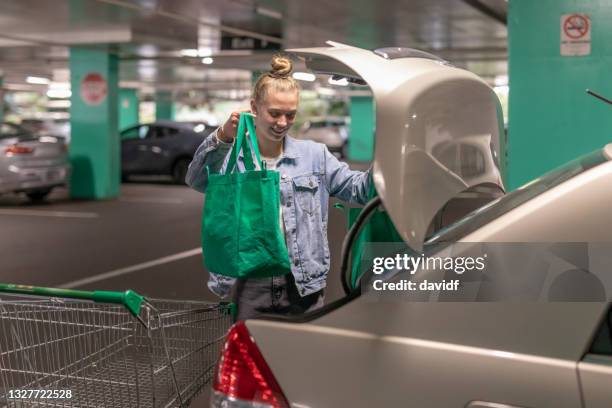 young woman putting shopping in the car - shopping australia stockfoto's en -beelden