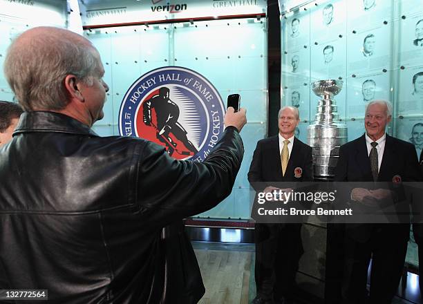 Marty Howe takes a photo of his brother and father, 2011 Hall of Fame inductee Mark Howe and hockey legend Gordie Howe during a photo opportunity at...