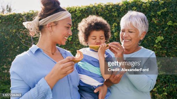 shot of a happy family standing outside and bonding while eating fruit - disruptaging stock pictures, royalty-free photos & images