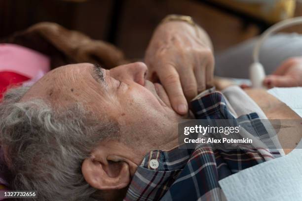 infirmière - technicien médical effectue l’examen des géurailles cardiaques à ultrasons à la maison pour le patient masculin âgé de 97 ans, à l’aide d’un appareil à ultrasons portable. - old ultrasound machine photos et images de collection