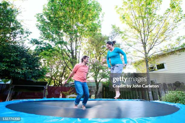 husband and wife jumping on trampoline - trampoline man stock pictures, royalty-free photos & images