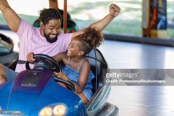 uma família afro-americana está desfrutando de carro de para-choques no parque de diversões. - parque de diversões edifício de entretenimento - fotografias e filmes do acervo