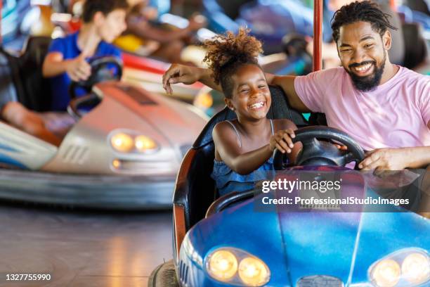 african-american father is driving in bumper car with his cute little daughter. - motorized vehicle riding stock pictures, royalty-free photos & images