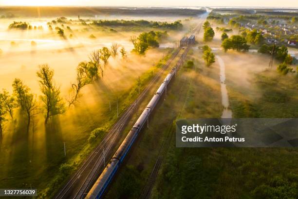 aerial view of passenger train on the railroad in misty dawn. railway passenger transportation - length stock pictures, royalty-free photos & images