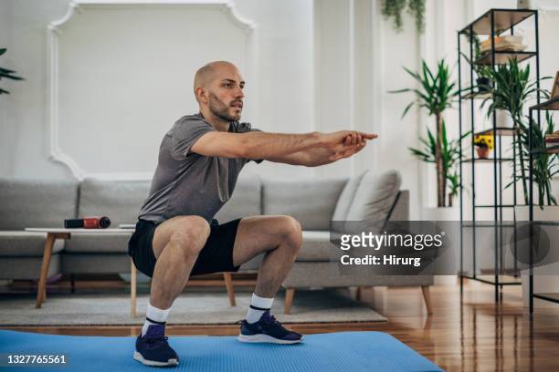 homem se exercitando em casa - squatting position - fotografias e filmes do acervo