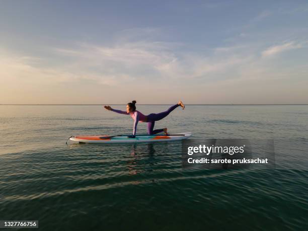 high angle shot of woman yoga together paddleboarding . - surf board foto e immagini stock