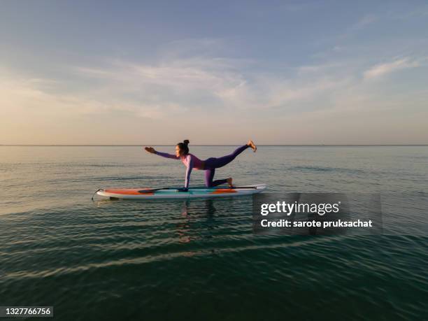 high angle shot of woman yoga together paddleboarding . - remo em pé imagens e fotografias de stock