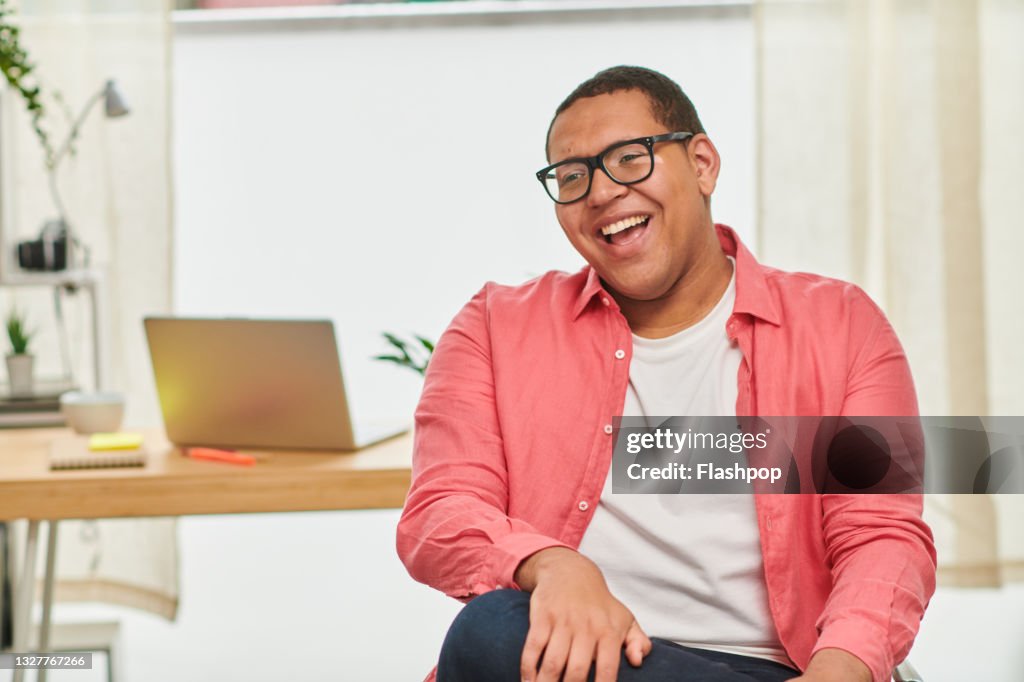 Portrait of happy, confident young man in office laughing