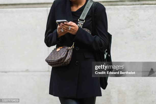 Guest wears a long black blazer jacket, black pants, silver rings, a brown LV monogram in coated canvas Multi-Pochette Accessoires crossbody bag from...