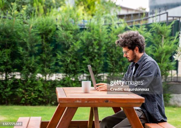 geschäftsmann, der am laptop im hinterhof seines hauses arbeitet - daily life in turkey stock-fotos und bilder