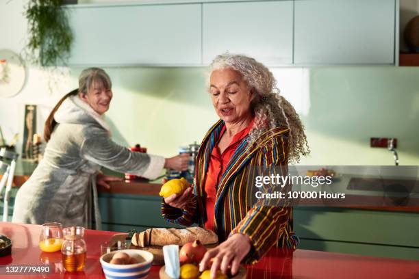 two flatmates in kitchen preparing breakfast - mature adult cooking stock pictures, royalty-free photos & images