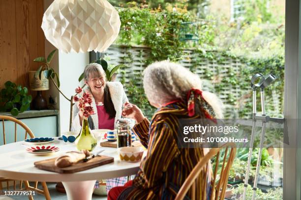 smiling mature woman chatting to friend at breakfast table - roommate bildbanksfoton och bilder