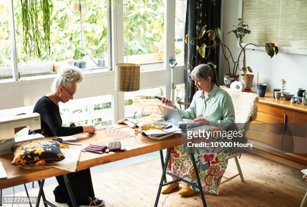 two female crafters working at dining room table - roommate fotografías e imágenes de stock