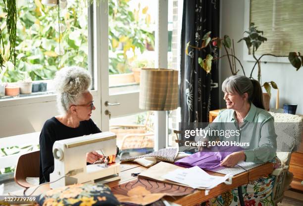 two flatmates chatting at dining room table with sewing machine - crafting together stock pictures, royalty-free photos & images