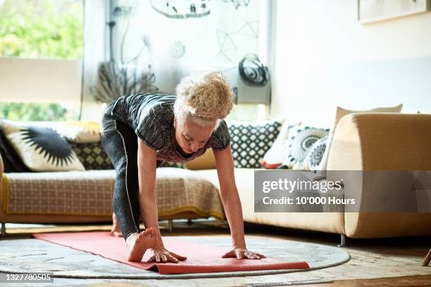 grey haired woman leaning forward in yoga position - forward thinking stock-fotos und bilder