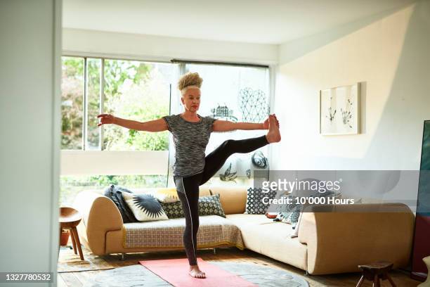 senior woman standing in balance yoga pose - home workout foto e immagini stock