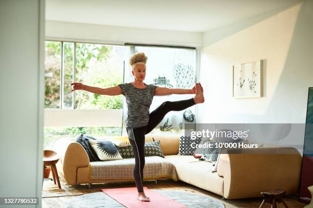 senior woman standing in balance yoga pose - home workout stock pictures, royalty-free photos & images