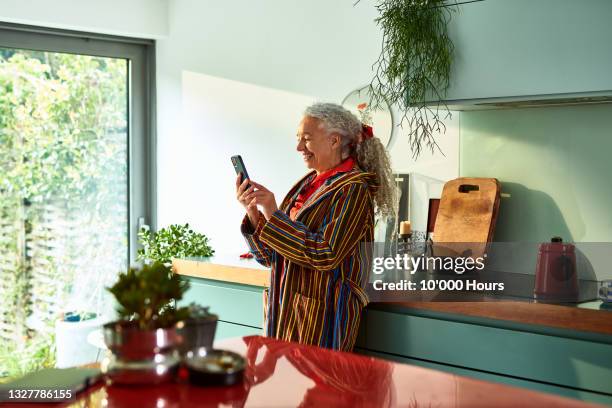 smiling grey haired woman speaking on video call - using phone foto e immagini stock