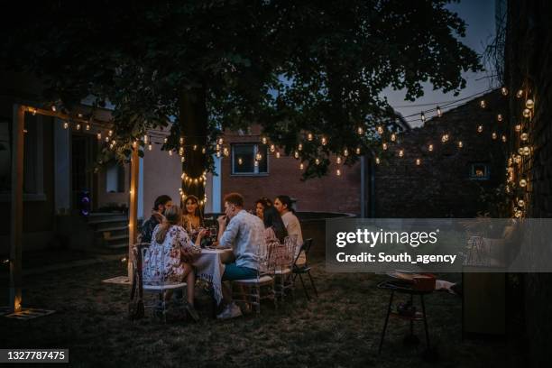 freunde auf dinnerparty im hinterhof - abenddämmerung stock-fotos und bilder