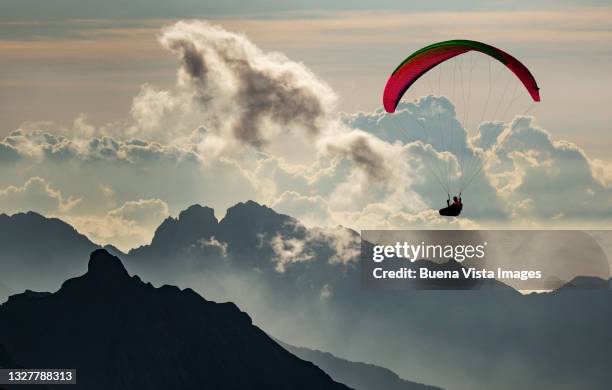 paraglider flying over mountains. - gleiten stock-fotos und bilder