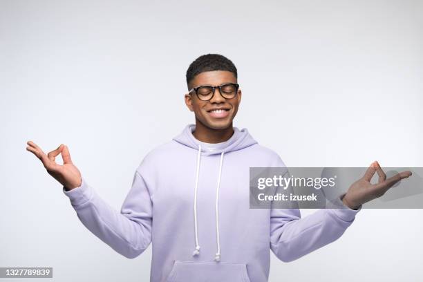 young man wearing lilac hoodie meditating - effortless stock pictures, royalty-free photos & images