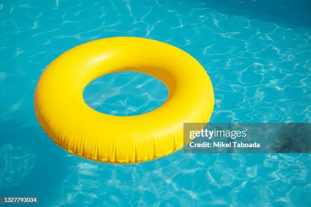 yellow float in blue swimming pool - float stockfoto's en -beelden