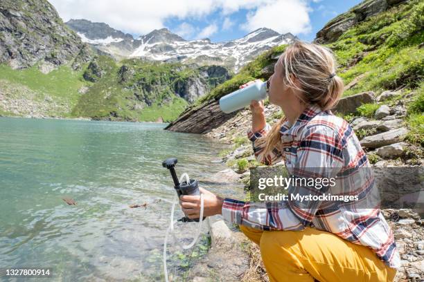 young women filters water from alpine lake - filtration stock pictures, royalty-free photos & images