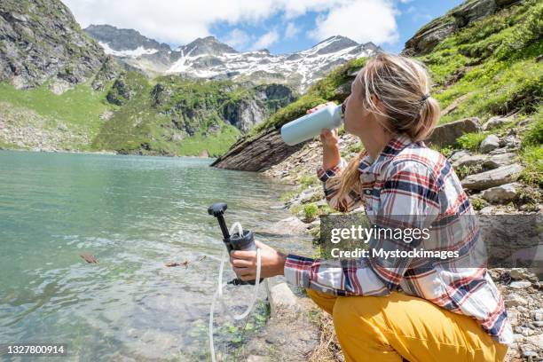 young women filters water from alpine lake - gourd bildbanksfoton och bilder