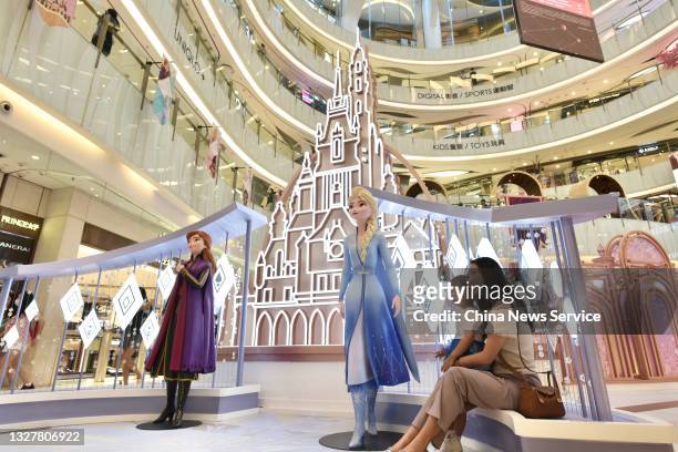 Woman and a child pose for photos with sculptures of Elsa and Anna characters from Disney film 'Frozen 2' at MOKO shopping mall on July 8, 2021 in...