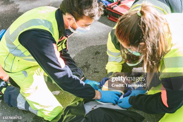 paramedics using a collar on a patient after a car crash - spoedeisende hulp stockfoto's en -beelden