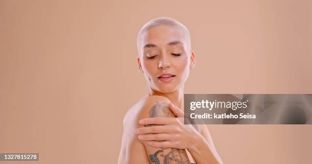 toma de estudio de una hermosa mujer joven de pie sobre un fondo de melocotón - tattoo fotografías e imágenes de stock