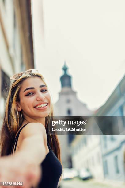 girl turning back to her partner exploring old town - novi sad stockfoto's en -beelden