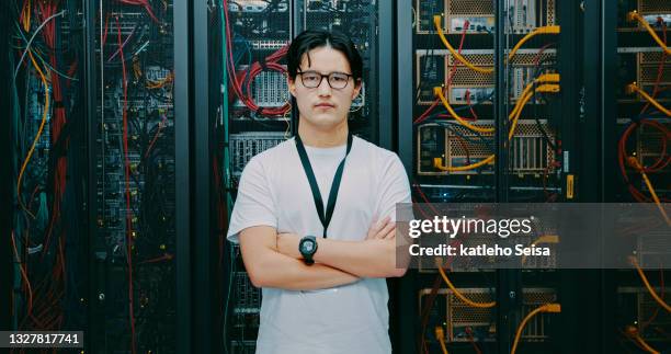 plan d’un jeune homme utilisant des écouteurs alors qu’il travaillait dans une salle de serveurs - technicien informatique photos et images de collection