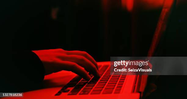 shot of a hacker using a laptop - hacker imagens e fotografias de stock