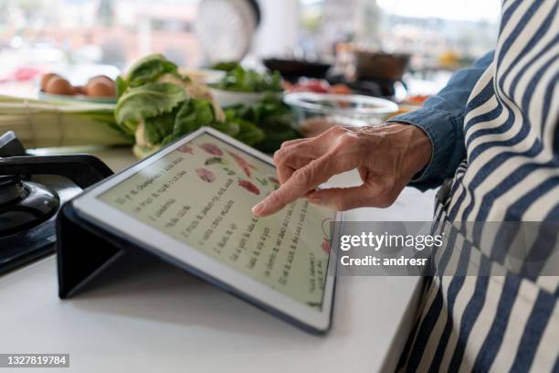 close-up on a woman following a recipe online while cooking at home - recipe stock pictures, royalty-free photos & images