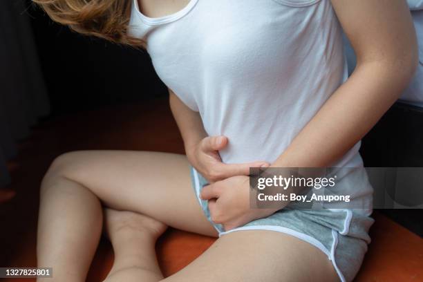 cropped shot of woman having painful stomachache or suffering from menstrual pain, period cramp or abdominal pain during pregnancy. - swollen fotografías e imágenes de stock