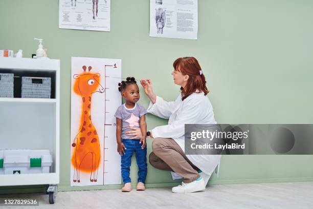 tiro de um médico medindo a altura de uma menina adorável durante uma consulta - instrumento de medição - fotografias e filmes do acervo