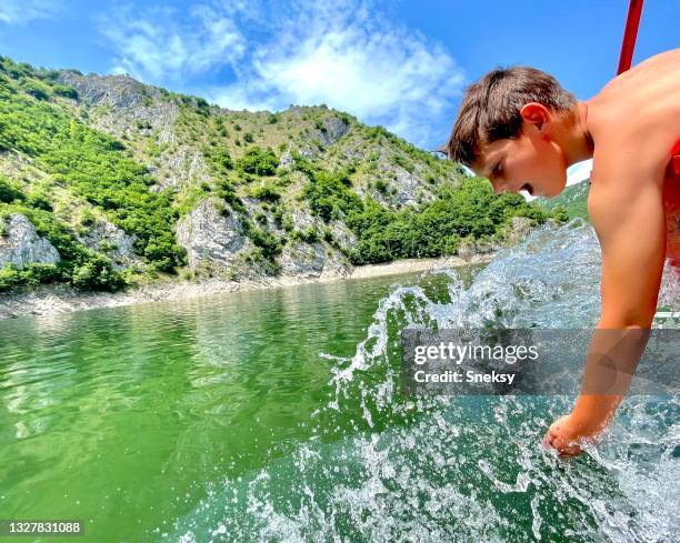 boy is enjoying in boat ride, splashing water. - meadow brook imagens e fotografias de stock